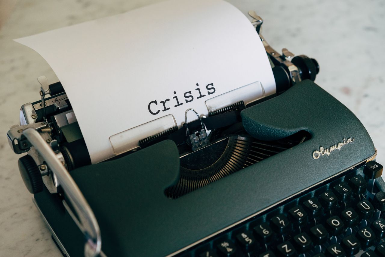 Close-up of a vintage typewriter with the word Crisis typed on paper.